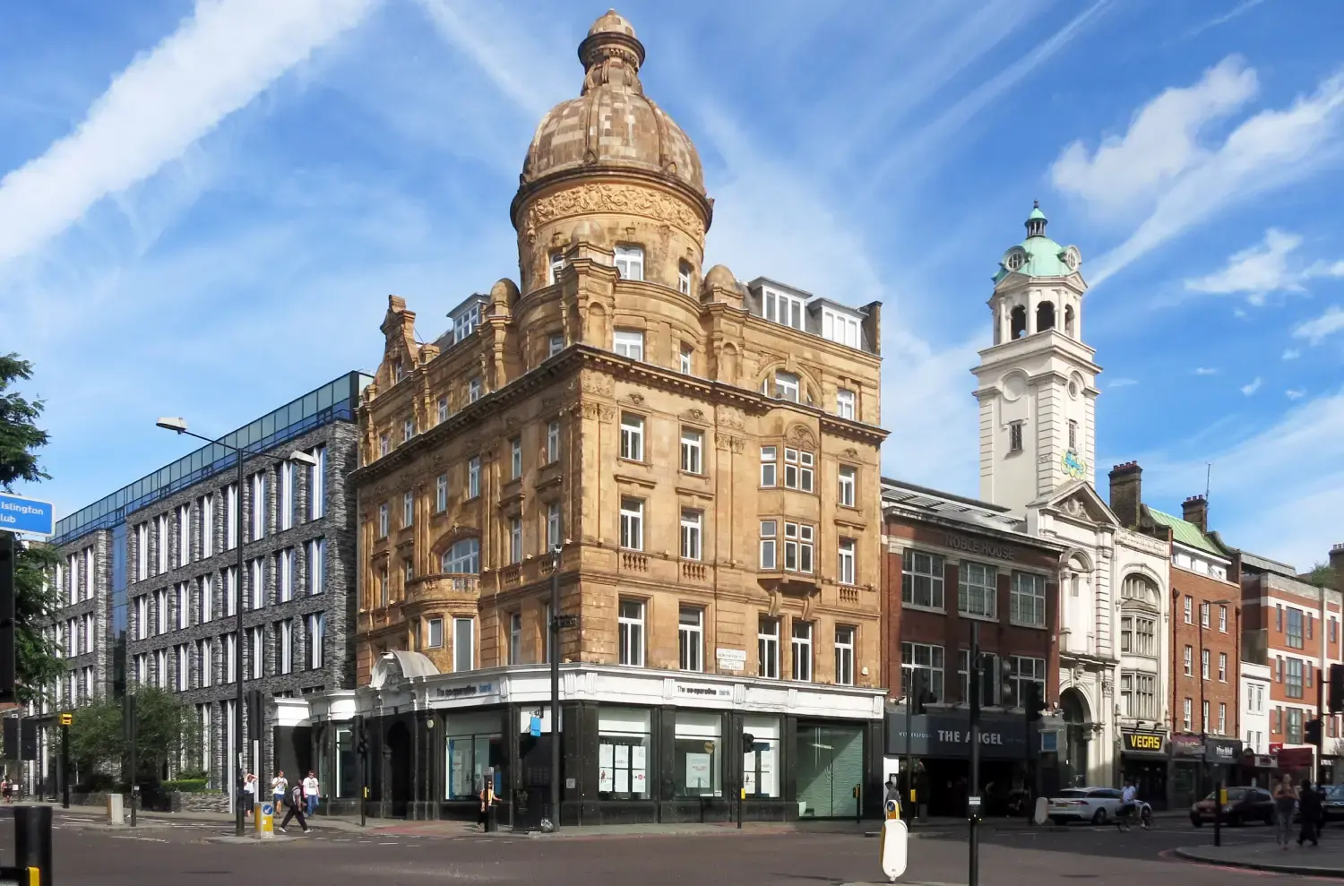 The domed Angel building on the corner of Islington High Street, with the clock tower of Islington Town Hall rising behind it.