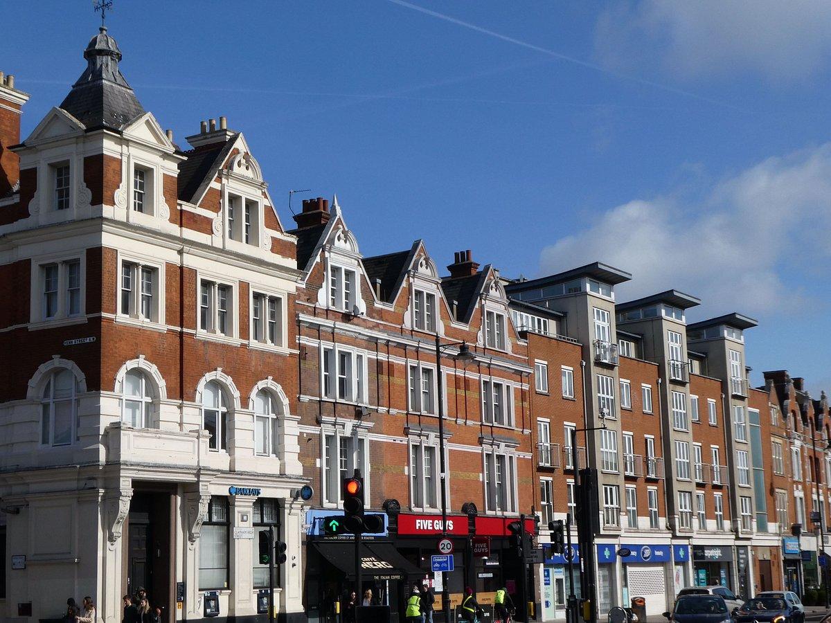 A red brick Victorian parade along Clapham High Street, shopfronts at street level and flats in the gables above.